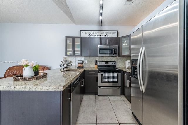 18481 NW 22nd St, Pembroke Pines, FL 33029 - kitchen with stainless steel appliances, a peninsula, glass insert cabinets, a textured ceiling, and light tile patterned flooring