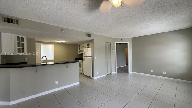1145 Lake Shore Dr Unit 205, Lake Park, FL 33403 - kitchen featuring white appliances, a breakfast bar area, light tile patterned floors, dark countertops, and glass insert cabinets