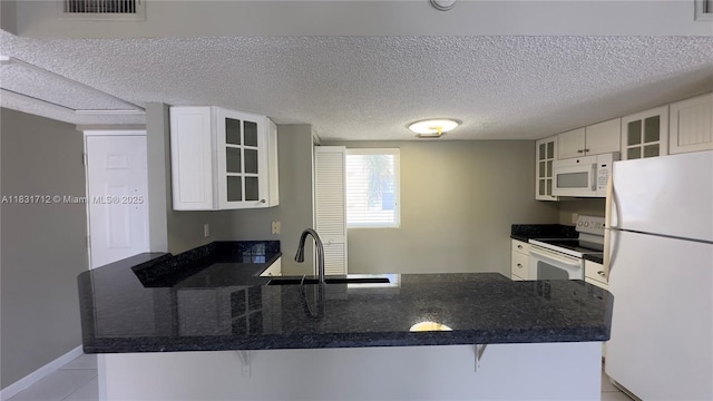 1145 Lake Shore Dr Unit 205, Lake Park, FL 33403 - kitchen with white appliances, a peninsula, white cabinets, glass insert cabinets, and light tile patterned floors