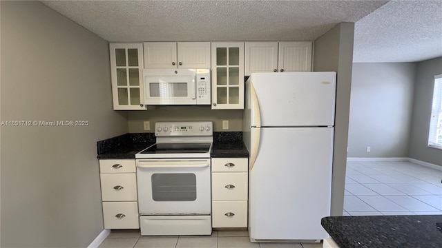 1145 Lake Shore Dr Unit 205, Lake Park, FL 33403 - kitchen with white appliances, a textured ceiling, light tile patterned floors, white cabinets, and glass insert cabinets