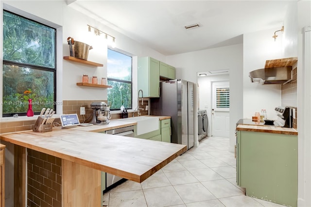 7900 SW Springhaven Ave, Indian Town, FL 34956 - kitchen featuring green cabinetry, open shelves, washing machine and dryer, and wooden counters