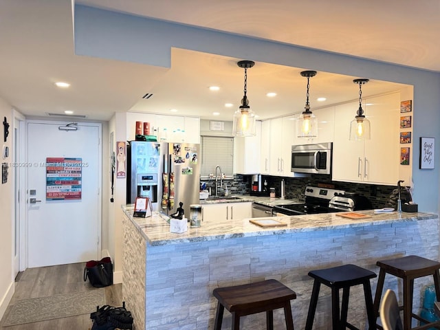 400 N Surf Rd Unit 804, Hollywood, FL 33019 - kitchen featuring stainless steel appliances, a peninsula, dark wood-style floors, light stone counters, and hanging light fixtures