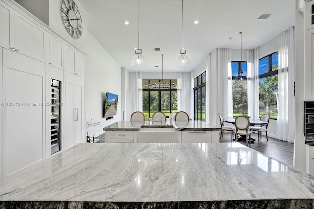11056 Blackhawk Blvd, Davie, FL 33328 - kitchen with a large island with sink, white cabinetry, recessed lighting, and light stone counters