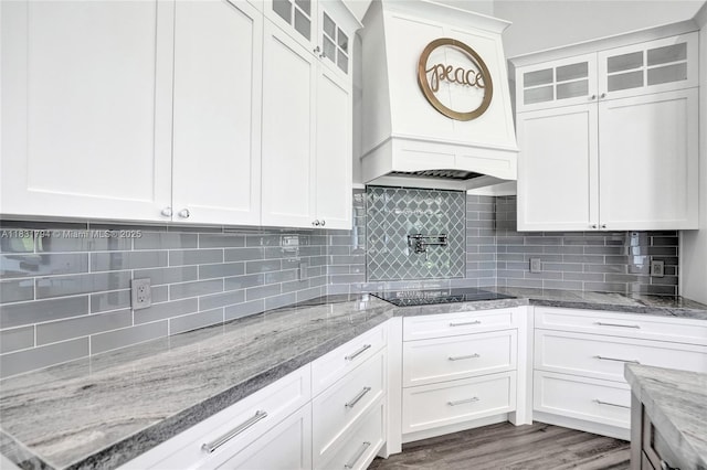 11056 Blackhawk Blvd, Davie, FL 33328 - kitchen with custom exhaust hood, black electric cooktop, glass insert cabinets, backsplash, and white cabinets