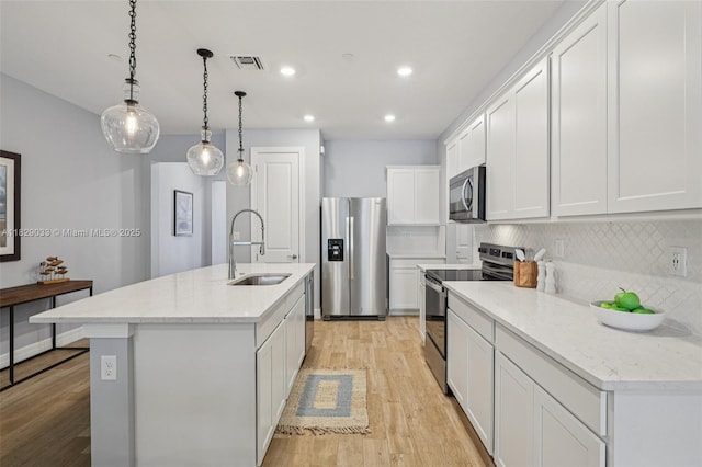 8367 NW 7th Pl Unit 0, Plantation, FL 33324 - kitchen with stainless steel appliances, light wood-style flooring, tasteful backsplash, a kitchen island with sink, and white cabinetry