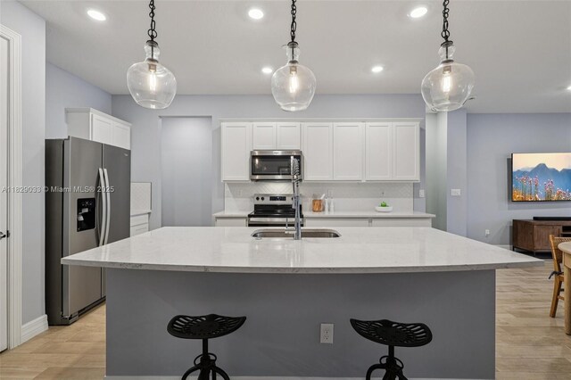 8367 NW 7th Pl Unit 0, Plantation, FL 33324 - kitchen featuring stainless steel appliances, light wood finished floors, recessed lighting, a kitchen breakfast bar, and white cabinetry