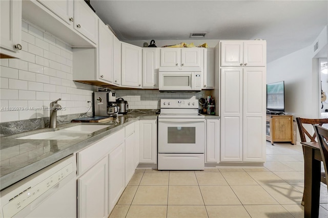 1884 Juno Rd, North Palm Beach, FL 33408 - kitchen featuring white appliances, backsplash, light tile patterned flooring, and white cabinetry