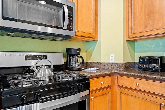 7661 Heritage Crossing Way Unit 102, Kissimmee, FL 34747 - kitchen with stainless steel appliances, brown cabinetry, and dark stone countertops