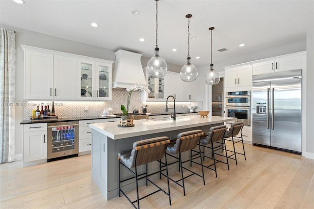 9369 Crestview Cir, Palm Beach Gardens, FL 33412 - kitchen featuring stainless steel appliances, beverage cooler, custom range hood, decorative backsplash, and a breakfast bar area