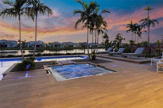 9369 Crestview Cir, Palm Beach Gardens, FL 33412 - pool at dusk featuring a swimming pool, an in-ground hot tub, a fenced backyard, and a patio