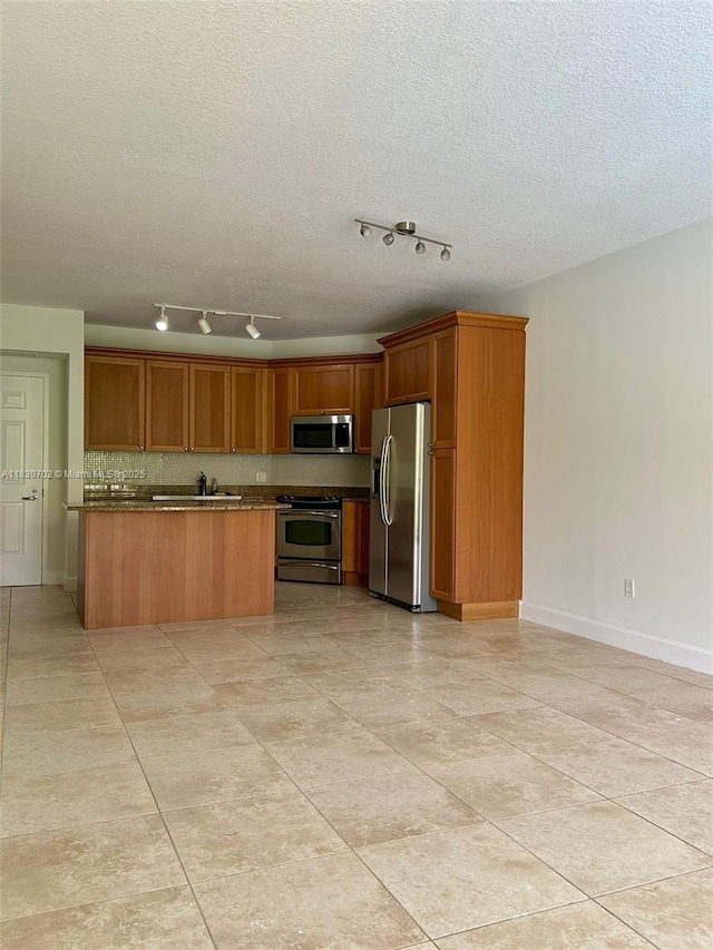 55 Merrick Way Unit 711, Coral Gables, FL 33134 - kitchen featuring appliances with stainless steel finishes, brown cabinetry, rail lighting, a textured ceiling, and light tile patterned floors