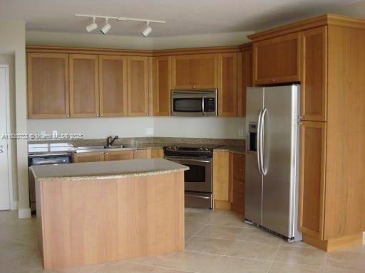 55 Merrick Way Unit 711, Coral Gables, FL 33134 - kitchen with stainless steel appliances, light tile patterned floors, a center island, and brown cabinets