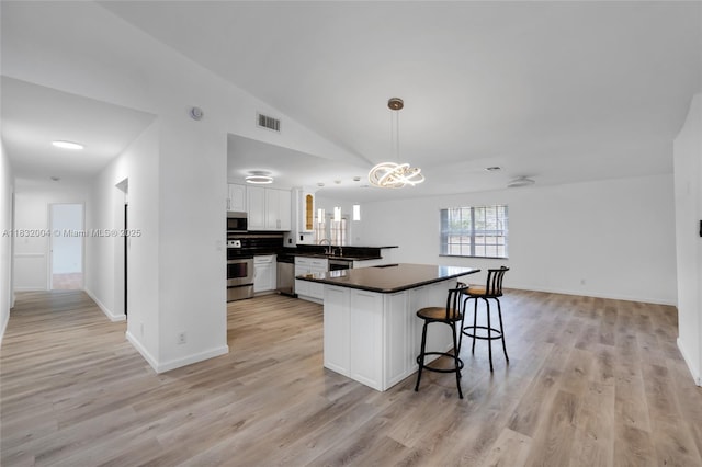 8031 NW 47th Ct, Lauderhill, FL 33351 - kitchen featuring dark countertops, white cabinetry, a peninsula, light wood-style floors, and lofted ceiling