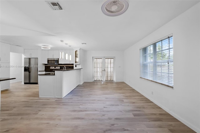 8031 NW 47th Ct, Lauderhill, FL 33351 - kitchen featuring stainless steel appliances, dark countertops, a peninsula, white cabinets, and light wood finished floors