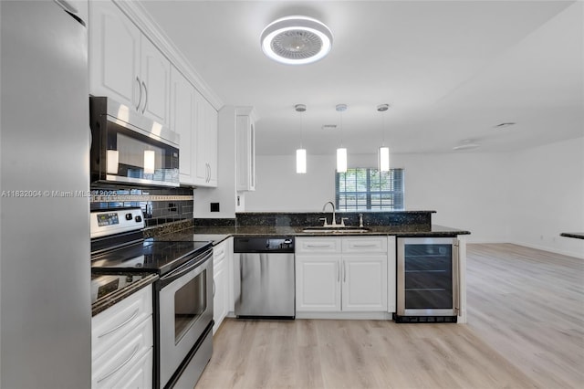 8031 NW 47th Ct, Lauderhill, FL 33351 - kitchen featuring appliances with stainless steel finishes, beverage cooler, a peninsula, light wood finished floors, and white cabinetry
