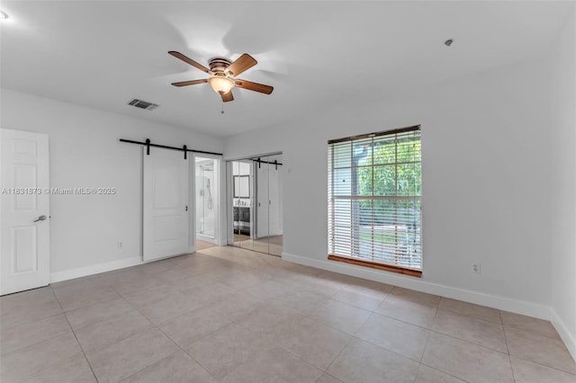 10600 SW 199th St, Cutler Bay, FL 33157 - unfurnished bedroom with a barn door, ensuite bath, light tile patterned floors, and a ceiling fan