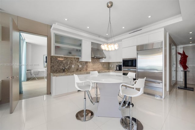 9703 Collins Ave Unit Ph-12, Bal Harbour, FL 33154 - kitchen featuring built in appliances, modern cabinets, a breakfast bar, tasteful backsplash, and white cabinetry