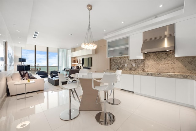 9703 Collins Ave Unit Ph-12, Bal Harbour, FL 33154 - kitchen featuring wall chimney range hood, decorative backsplash, light countertops, white cabinetry, and decorative light fixtures