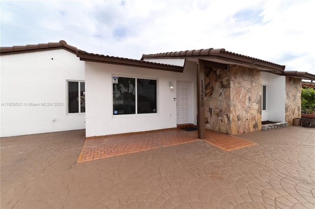 13250 SW 29th Ter, Miami, FL 33175 - rear view of property featuring a patio, stucco siding, stone siding, and a tile roof
