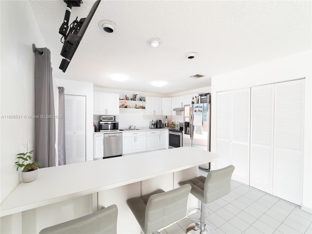 13250 SW 29th Ter, Miami, FL 33175 - kitchen featuring appliances with stainless steel finishes, open shelves, a peninsula, a breakfast bar area, and white cabinetry