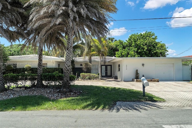 3210 Dover Rd, Pompano Beach, FL 33062 - ranch-style home featuring stucco siding, decorative driveway, french doors, and an attached garage