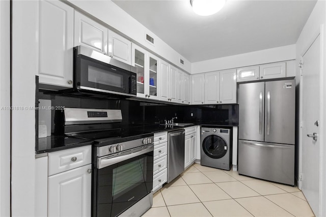 6770 Indian Creek Dr Unit 7A, Miami Beach, FL 33141 - kitchen with stainless steel appliances, washer / clothes dryer, dark countertops, white cabinets, and glass insert cabinets