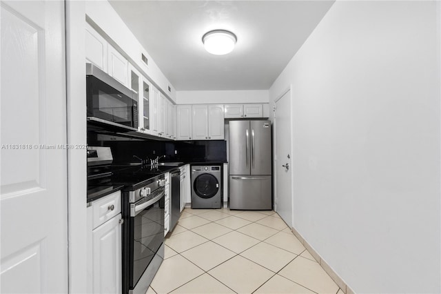 6770 Indian Creek Dr Unit 7A, Miami Beach, FL 33141 - kitchen with appliances with stainless steel finishes, washer / clothes dryer, dark countertops, white cabinets, and light tile patterned flooring