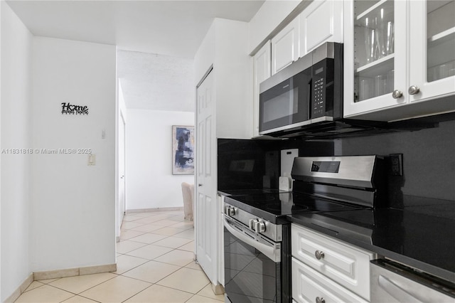 6770 Indian Creek Dr Unit 7A, Miami Beach, FL 33141 - kitchen with appliances with stainless steel finishes, white cabinets, glass insert cabinets, and dark countertops