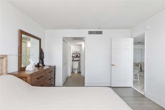 6770 Indian Creek Dr Unit 7A, Miami Beach, FL 33141 - bedroom featuring wood finished floors, a textured ceiling, and ensuite bath