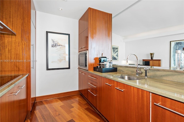 10295 Collins Ave Unit 1114, Bal Harbour, FL 33154 - kitchen featuring black microwave, wood finished floors, light stone countertops, and brown cabinets