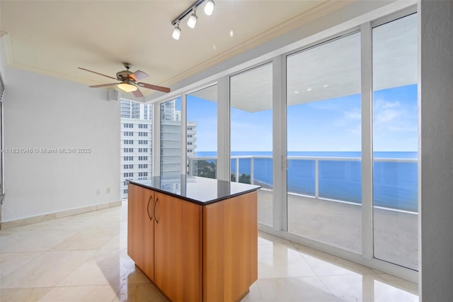 19111 Collins Ave Unit 801, Sunny Isles Beach, FL 33160 - kitchen with a water view, ceiling fan, dark countertops, a kitchen island, and light tile patterned floors