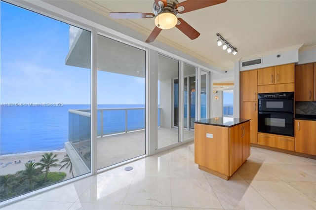 19111 Collins Ave Unit 801, Sunny Isles Beach, FL 33160 - kitchen featuring dark countertops, crown molding, a kitchen island, brown cabinets, and ceiling fan