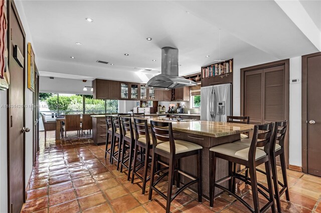 3520 Rockerman Rd, Miami, FL 33133 - kitchen with stainless steel fridge with ice dispenser, island exhaust hood, dark brown cabinets, a kitchen island, and glass insert cabinets