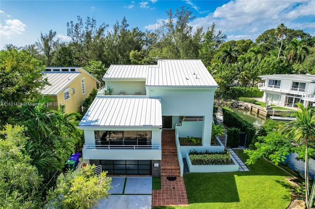3520 Rockerman Rd, Miami, FL 33133 - view of front of home with a standing seam roof, a metal roof, stucco siding, a front lawn, and a balcony