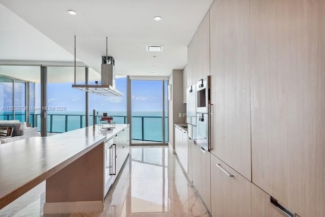 15701 Collins Ave Unit 2902, Sunny Isles Beach, FL 33160 - kitchen featuring expansive windows, modern cabinets, island exhaust hood, and light countertops
