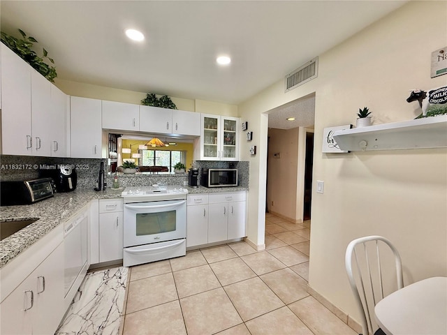 318 Lakeview Dr Unit 203, Weston, FL 33326 - kitchen featuring white appliances, decorative backsplash, white cabinets, light tile patterned floors, and light stone counters
