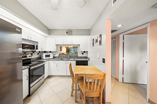 1601 SW 128th Ter Unit 209A, Pembroke Pines, FL 33027 - kitchen with stainless steel appliances, light tile patterned floors, white cabinets, a textured ceiling, and dark stone countertops