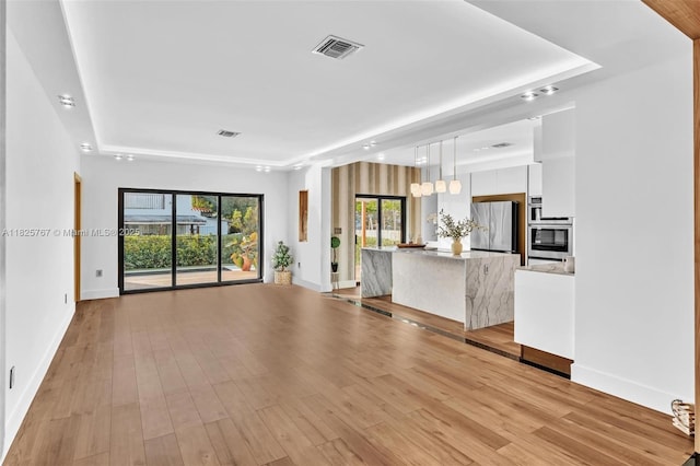 9448 Abbott Ave, Surfside, FL 33154 - unfurnished living room with a tray ceiling and light wood-style flooring