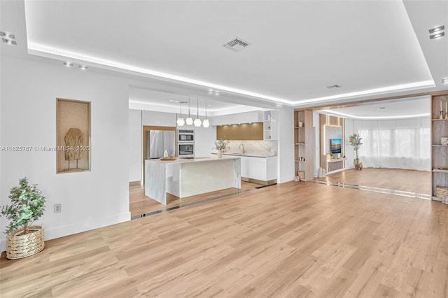9448 Abbott Ave, Surfside, FL 33154 - unfurnished living room featuring a tray ceiling and light wood-type flooring