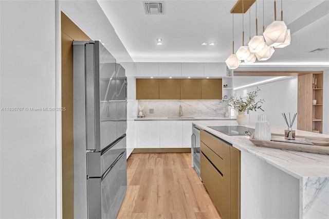 9448 Abbott Ave, Surfside, FL 33154 - kitchen with freestanding refrigerator, modern cabinets, backsplash, light wood-style flooring, and light stone countertops