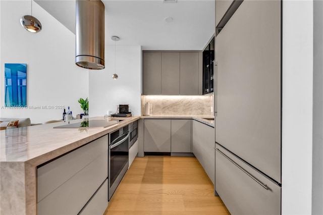 1100 Biscayne Blvd Unit 4305, Miami, FL 33132 - kitchen with black electric cooktop, a peninsula, stainless steel oven, gray cabinets, and wall chimney exhaust hood