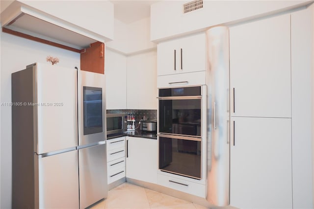 18101 Collins Ave Unit 701, Sunny Isles Beach, FL 33160 - kitchen featuring stainless steel appliances, white cabinets, dark countertops, and light tile patterned flooring