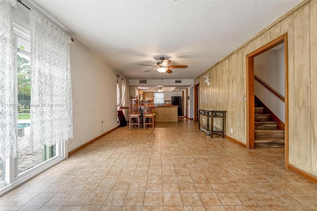 576 Marshall Rd, West Palm Beach, FL 33413 - unfurnished living room featuring a ceiling fan, wooden walls, and stairs