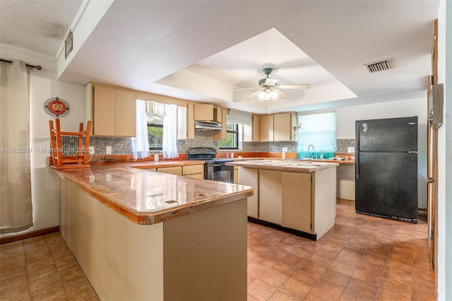 576 Marshall Rd, West Palm Beach, FL 33413 - kitchen featuring freestanding refrigerator, stainless steel electric range oven, a tray ceiling, cream cabinets, and under cabinet range hood