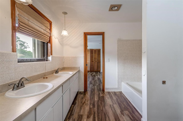 576 Marshall Rd, West Palm Beach, FL 33413 - bathroom with tile walls, wood finished floors, a bath, double vanity, and wainscoting