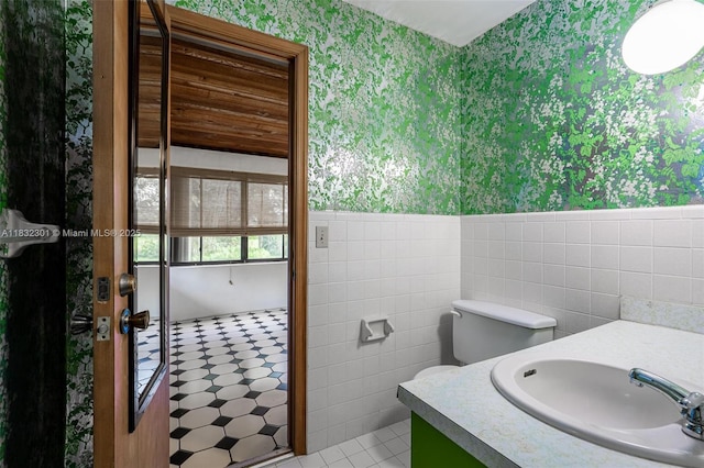 576 Marshall Rd, West Palm Beach, FL 33413 - bathroom with wallpapered walls, wainscoting, tile walls, and vanity