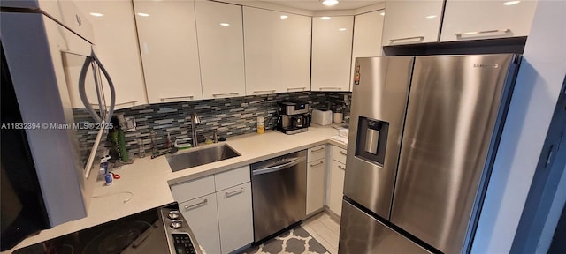 3522 NE 171st St Unit 104, North Miami Beach, FL 33160 - kitchen with appliances with stainless steel finishes, white cabinetry, light countertops, and decorative backsplash