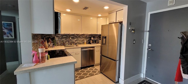 3522 NE 171st St Unit 104, North Miami Beach, FL 33160 - kitchen with stainless steel appliances, light countertops, backsplash, white cabinetry, and recessed lighting