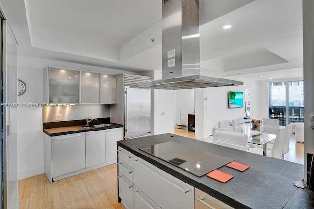 18201 Collins Ave Unit 1202, Sunny Isles Beach, FL 33160 - kitchen featuring island exhaust hood, a raised ceiling, black electric stovetop, stainless steel refrigerator, and dark countertops