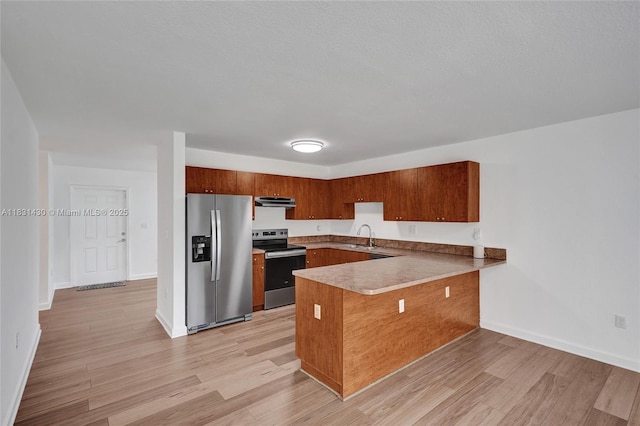 12254 SW 217th St, Miami, FL 33170 - kitchen with stainless steel appliances, a peninsula, light wood-style floors, brown cabinetry, and under cabinet range hood